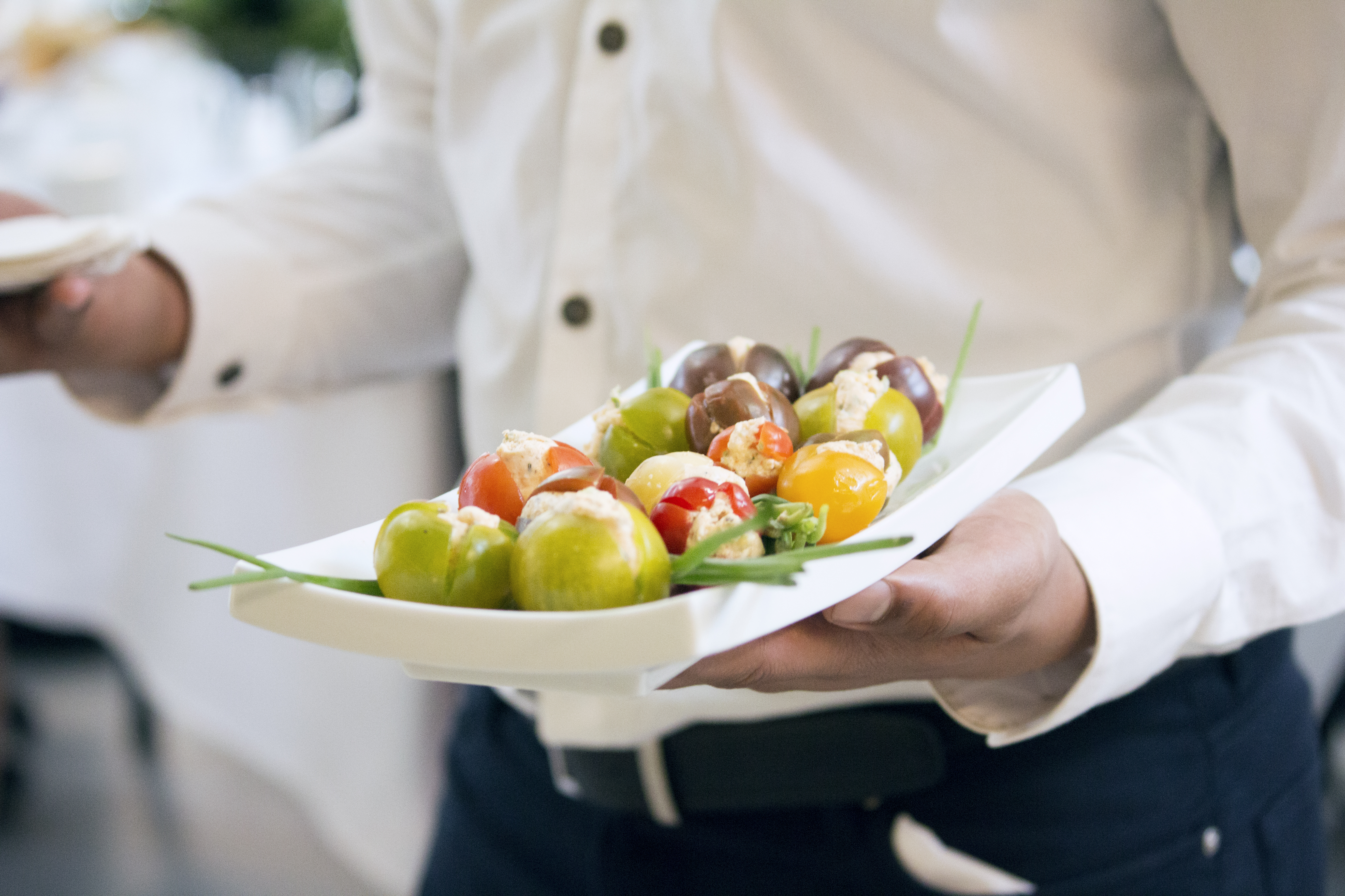 Waiter holding a tray of stuffed tomatoes.