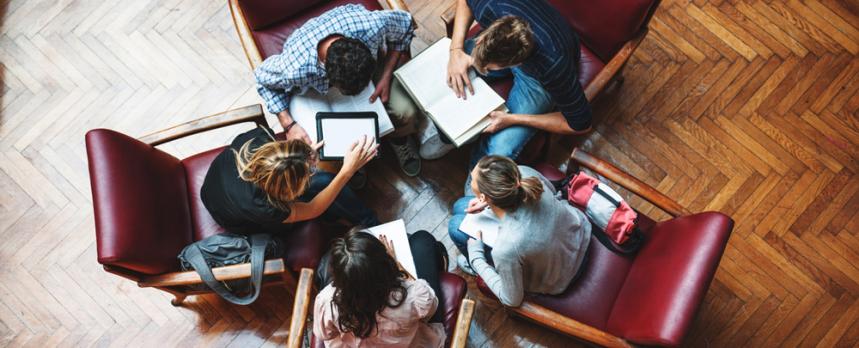 Image of students captured from above discussing seating on chairs