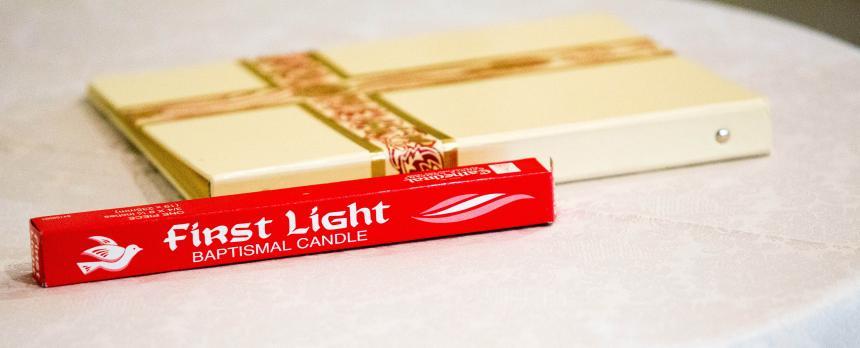 Image of a notebook with a Christian Cross on it and a pack of candles on a table