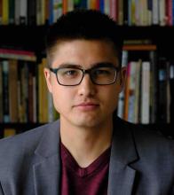 Galen Wats posing in a business suit in front of a bookshelf